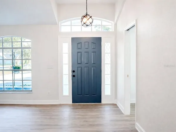an empty room with wooden floor cabinet and windows