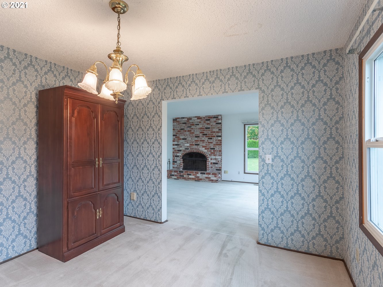 22835 Southeast Tillstrom Road Damascus, OR 97089 - Photo 12 of 32 a view of a livingroom with a fireplace cabinet and a chandelier