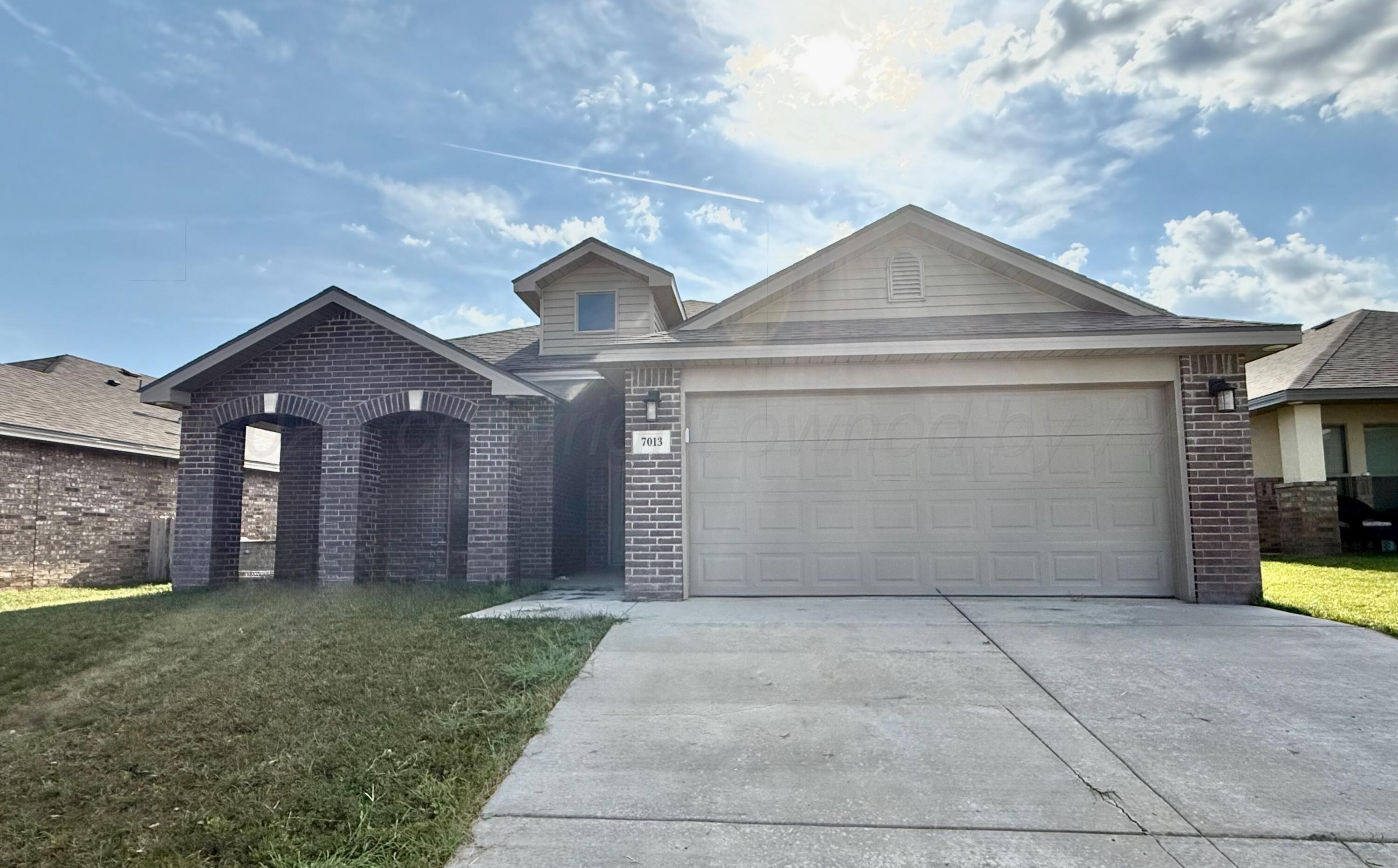 a view of a brick house with a yard and large tree