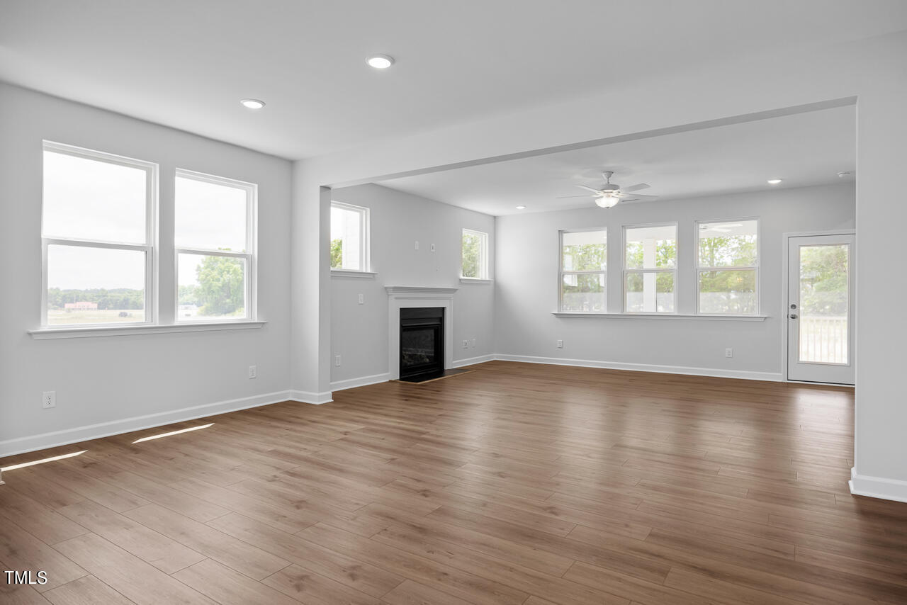 63 Golden Leaf Farms Road, Unit 12 Angier, NC 27501 - Photo 12 of 25 an empty room with wooden floor fireplace and windows