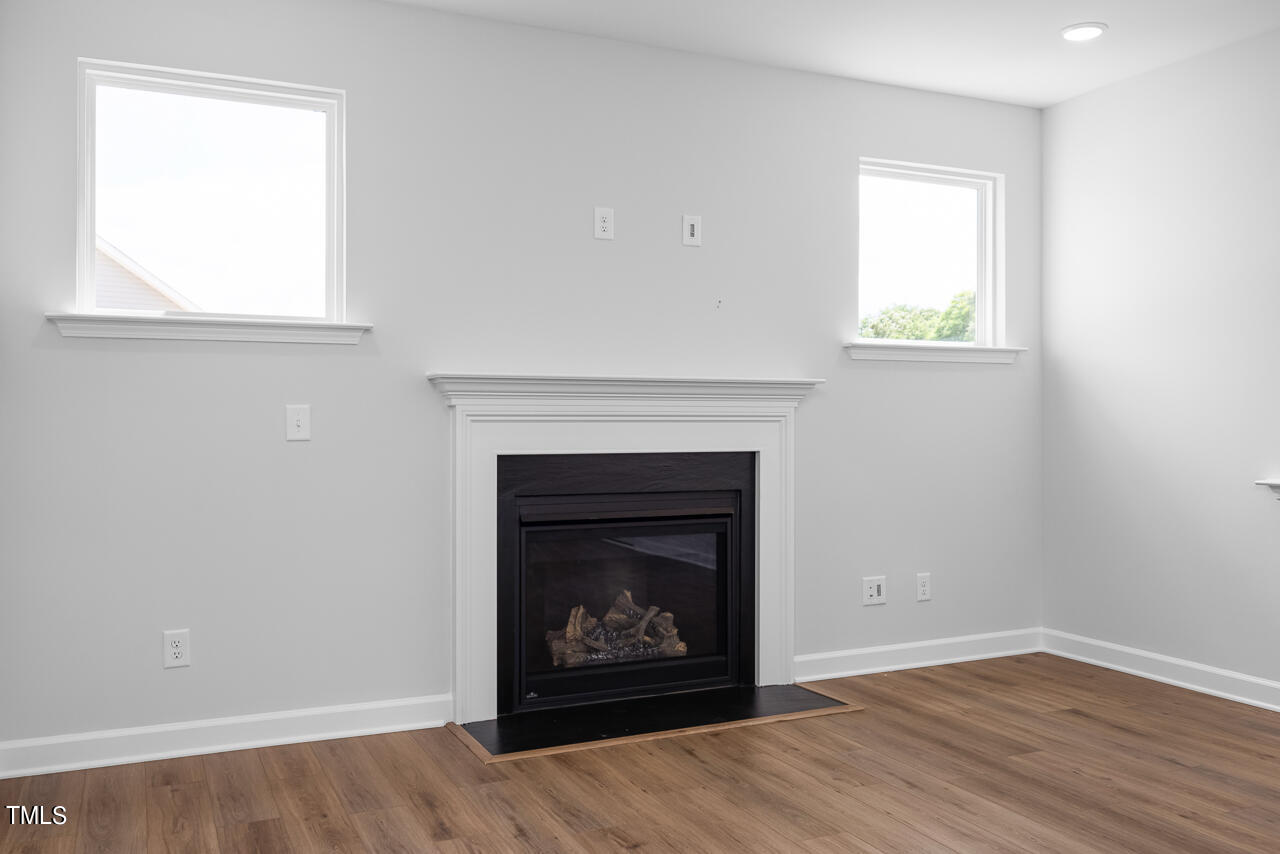 63 Golden Leaf Farms Road, Unit 12 Angier, NC 27501 - Photo 13 of 25 an empty room with a fireplace and wooden floor