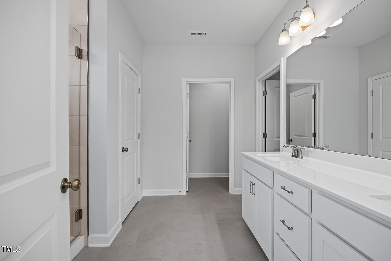 63 Golden Leaf Farms Road, Unit 12 Angier, NC 27501 - Photo 18 of 25 a spacious bathroom with a double vanity sink a large mirror and a shower