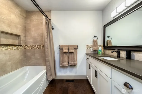 a en suite bathroom with a granite countertop sink and a bathtub