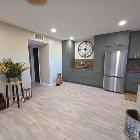 a big room with chandelier fan and wooden floor