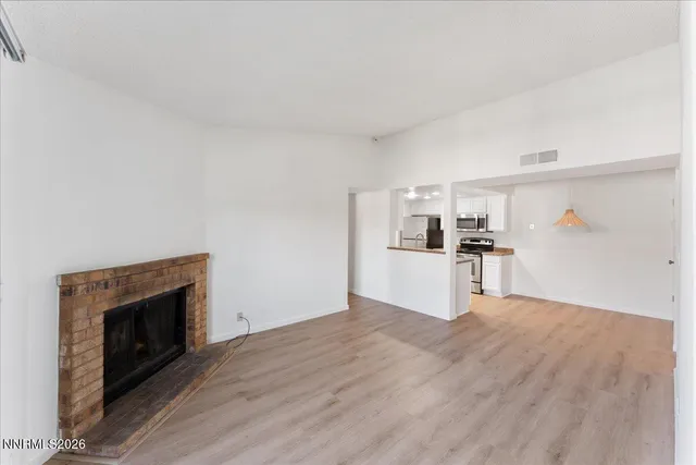 a view of kitchen and empty room with wooden floor
