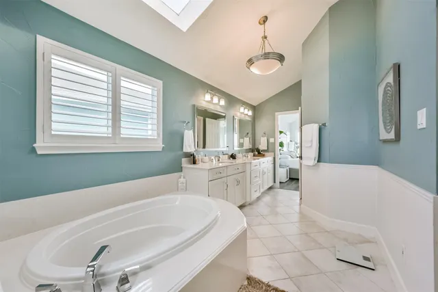 a spacious bathroom with a double vanity sink mirror and a bathtub