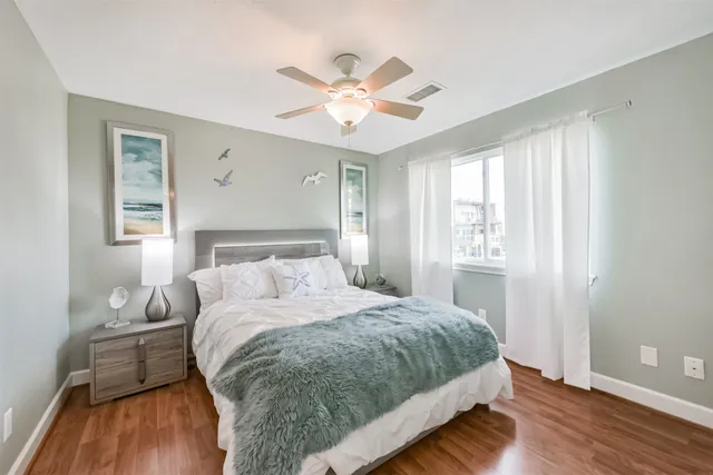 an empty room with wooden floor chandelier fan and windows