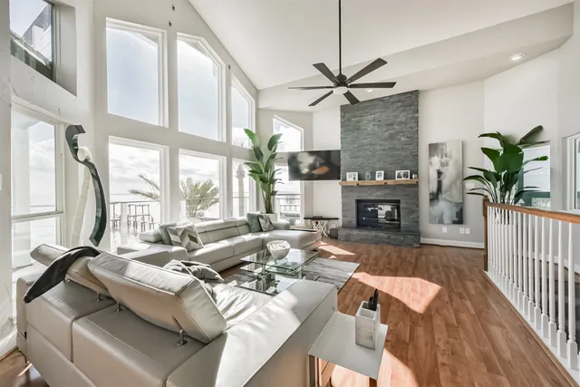 a living room with furniture a ceiling fan a lamp and a window