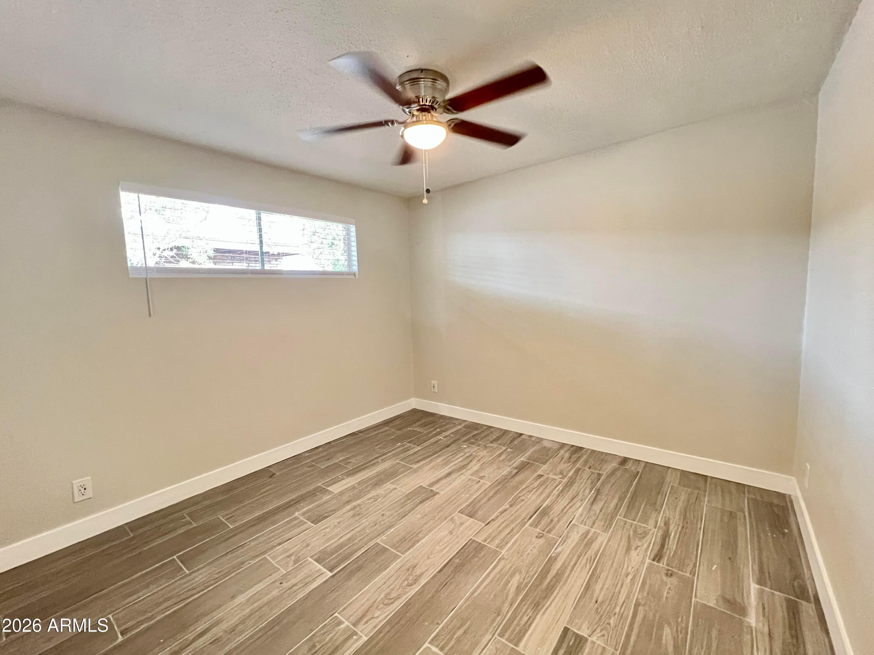 1973 East 10th Street, Unit B Tempe, AZ 85281 - Photo 6 of 6 an empty room with wooden floor and ceiling fan
