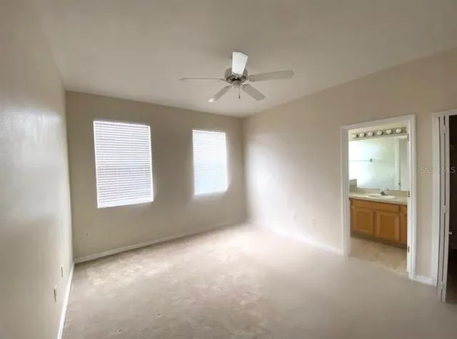 a view of an empty room with a window and a kitchen