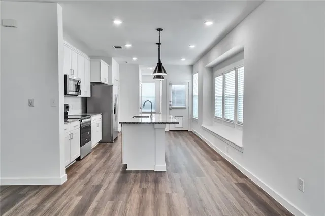 a large kitchen with white cabinets stainless steel appliances