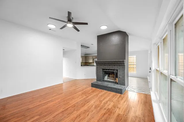 an empty room with wooden floor fireplace and windows