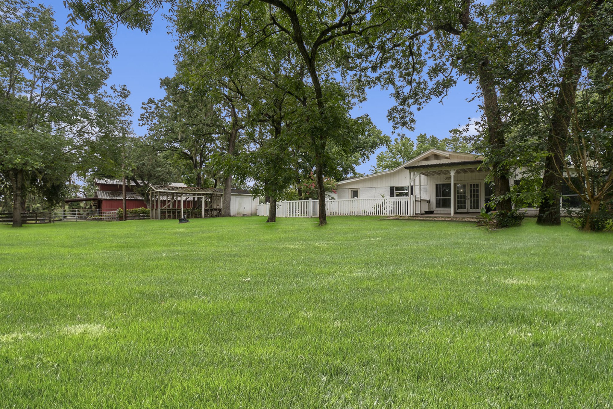 7363 County Line Road Willis, TX 77378 - Photo 32 of 34 Expansive backyard oasis featuring a lush lawn, mature trees, and a charming patio—perfect for outdoor gatherings and relaxation.