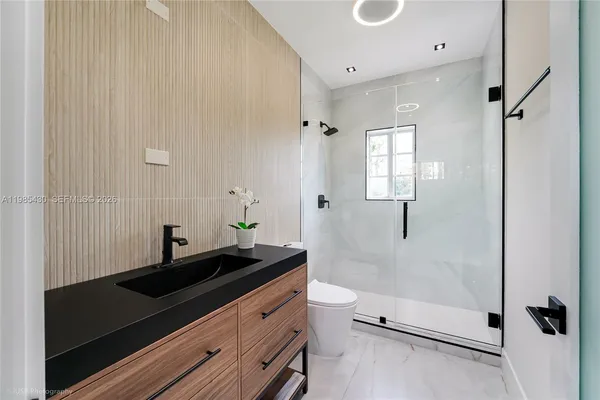 a bathroom with a granite countertop sink a toilet and shower
