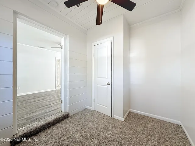 an empty room with ceiling fan and window