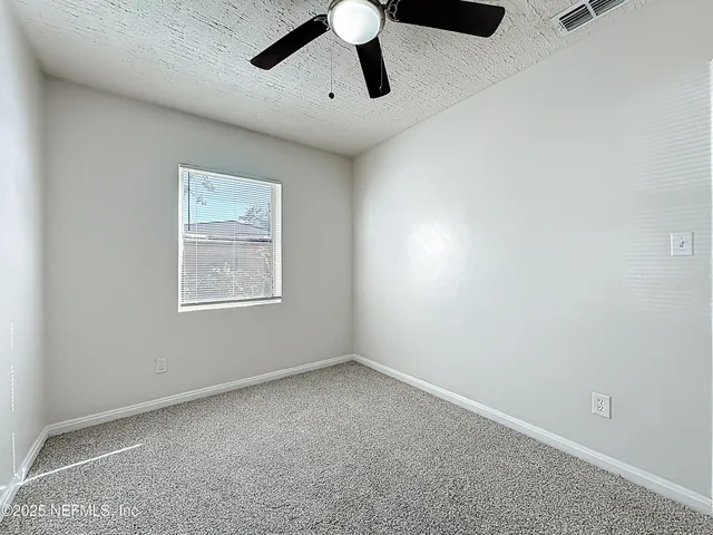 an empty room with chandelier fan