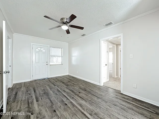 a view of empty room with wooden floor and ceiling fan