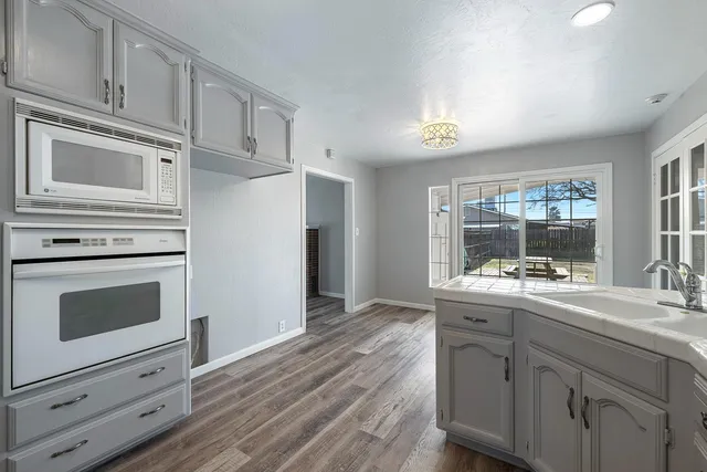 a kitchen with stainless steel appliances white cabinets and wooden floor