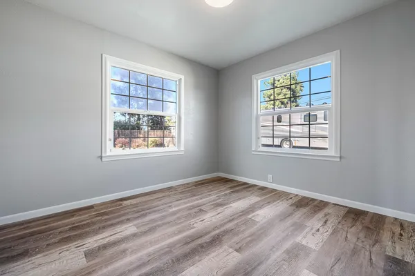 a view of an empty room with wooden floor fireplace and a window