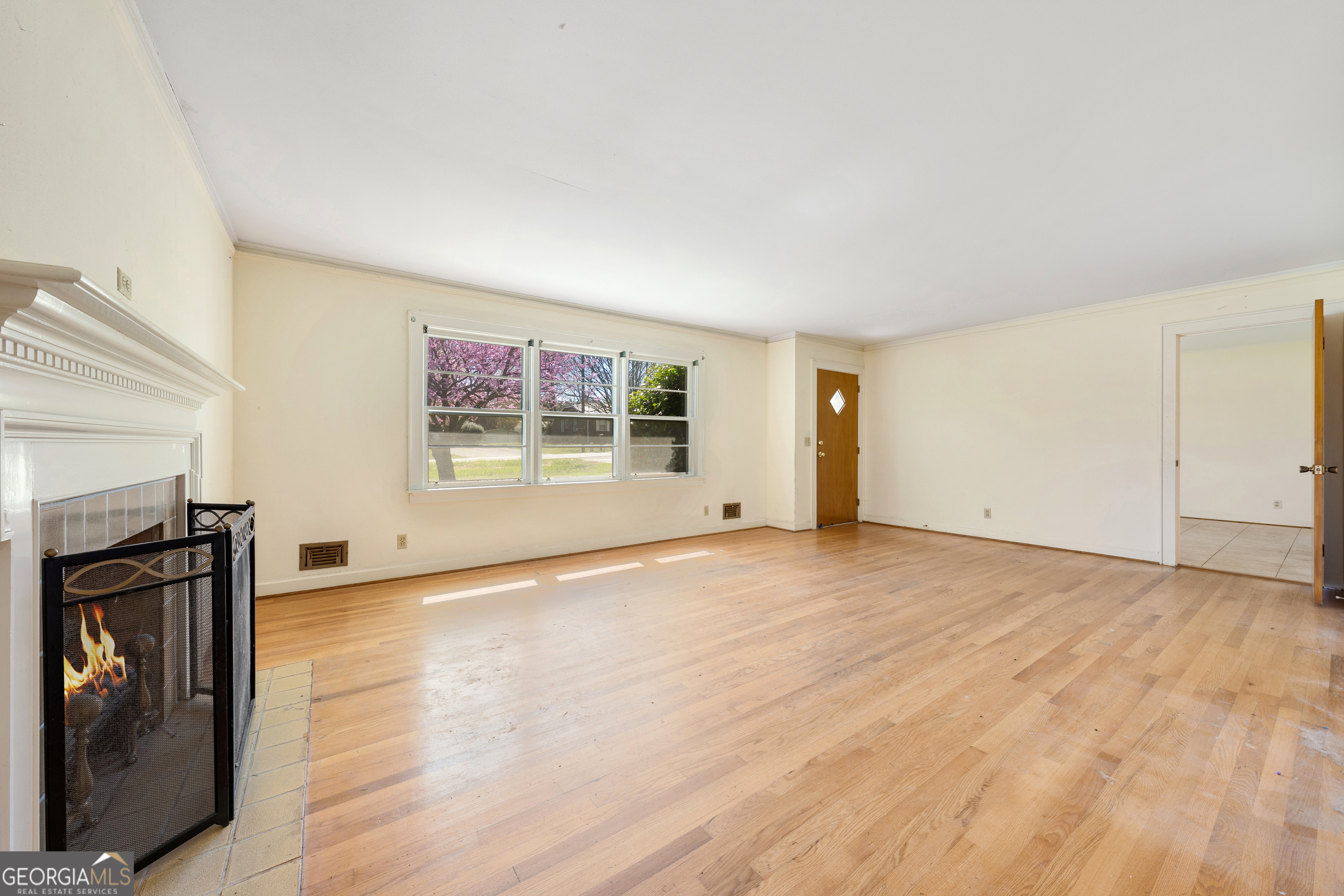 868 Fairview Street Hartwell, GA 30643 - Photo 8 of 42 an empty room with wooden floor fireplace and windows
