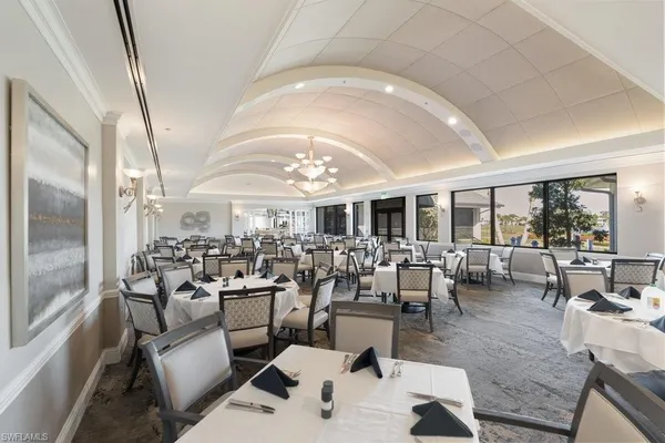 a living room with lots of furniture a chandelier and a view of kitchen