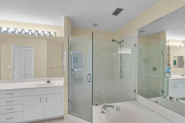 a bathroom with a tub shower sink mirror and shower