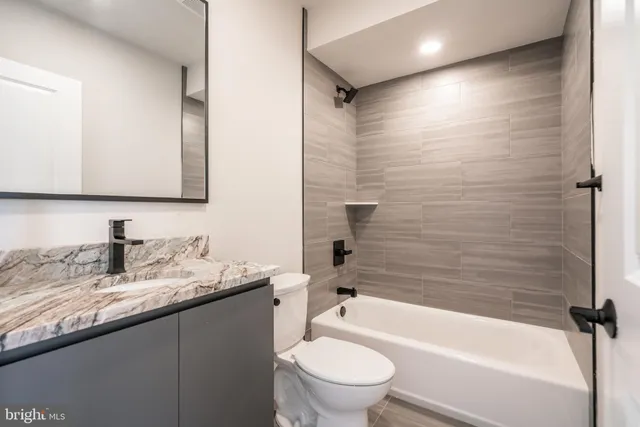a bathroom with a granite countertop sink toilet and shower