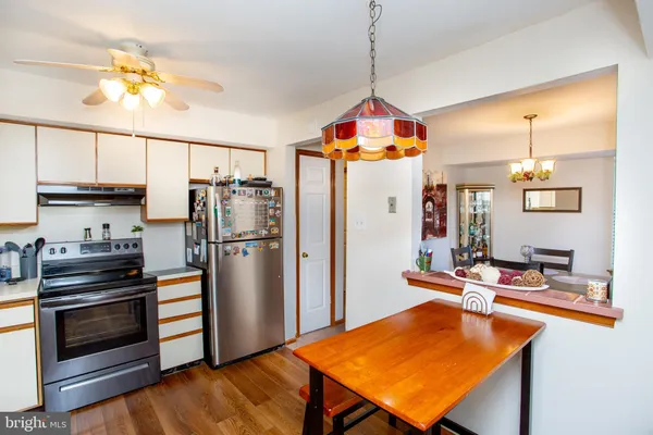 a kitchen with stainless steel appliances granite countertop a refrigerator a stove and a sink with chandelier