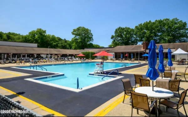a view of swimming pool with seating area and trees in the background