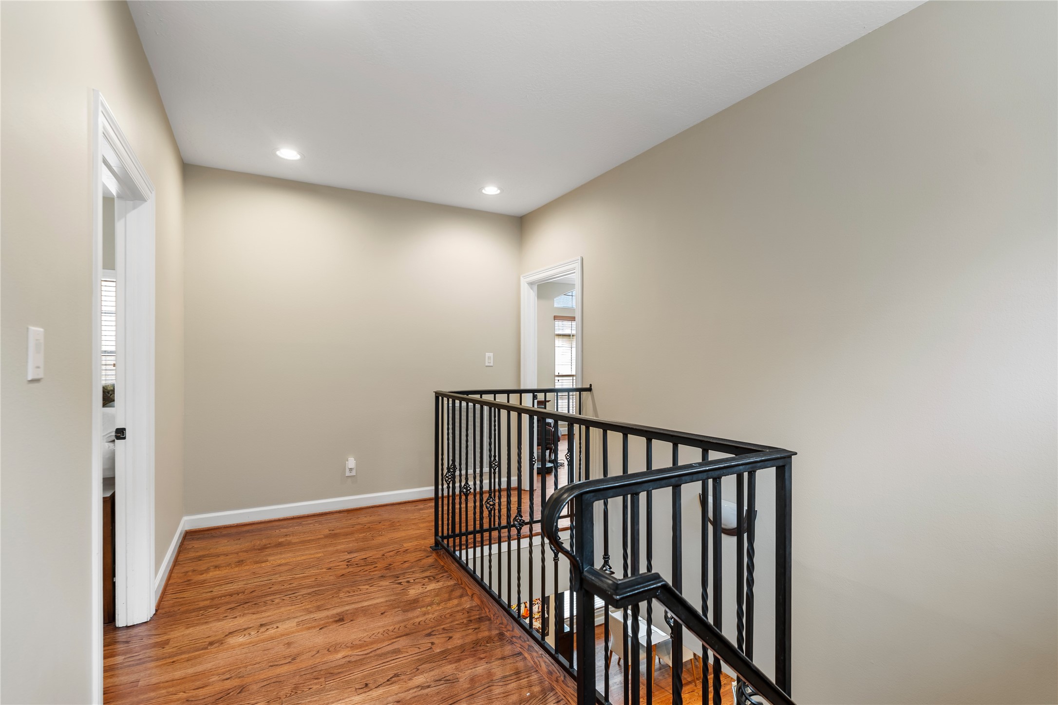 408 Fowler Street Houston, TX 77007 - Photo 16 of 24 This upper-level landing showcases beautiful hardwood floors and stylish wrought iron railings, connecting bedrooms with elegance.