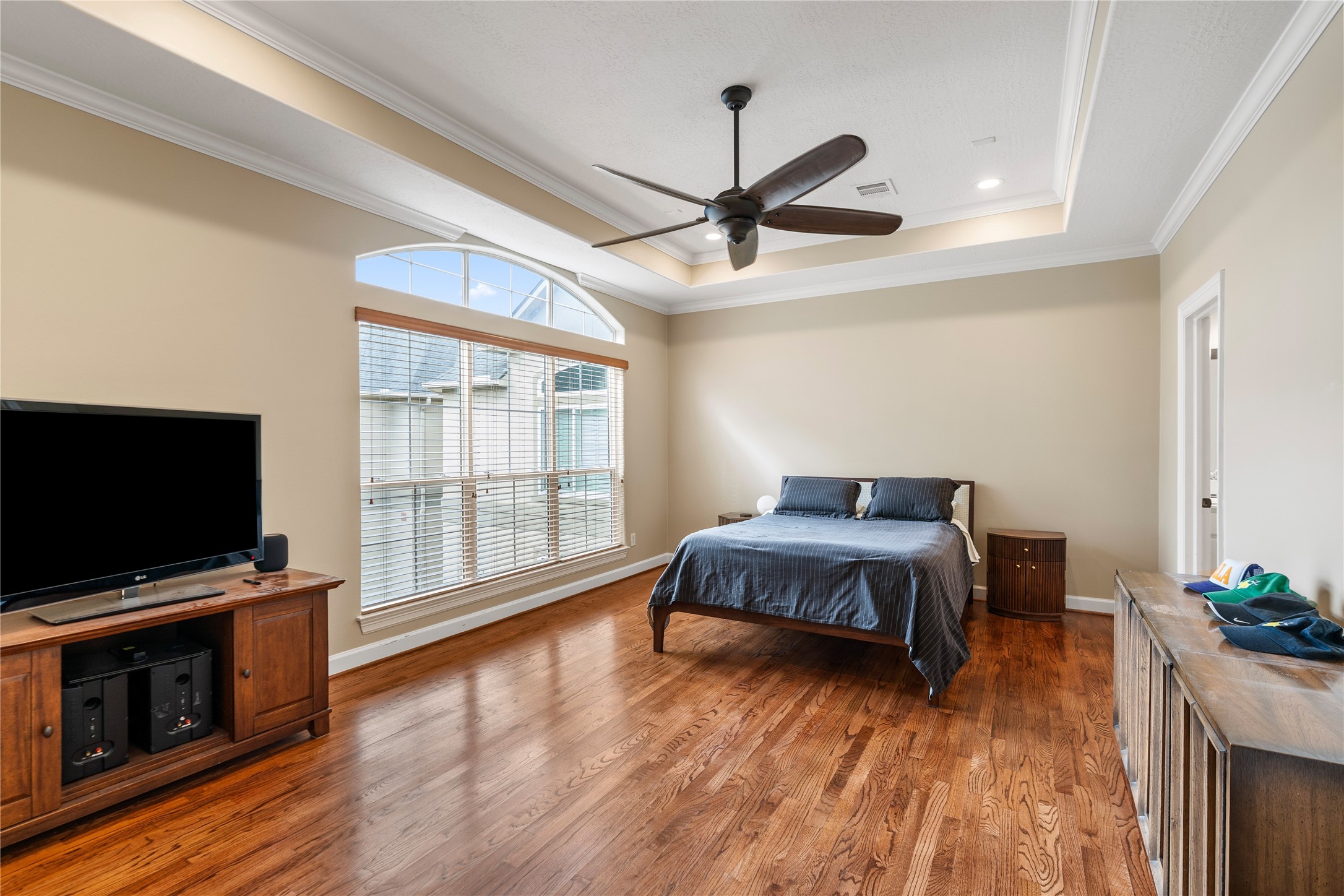 408 Fowler Street Houston, TX 77007 - Photo 17 of 24 Retreat to the oversized primary bedroom featuring tray ceilings, rich hardwood floors, and abundant natural light.