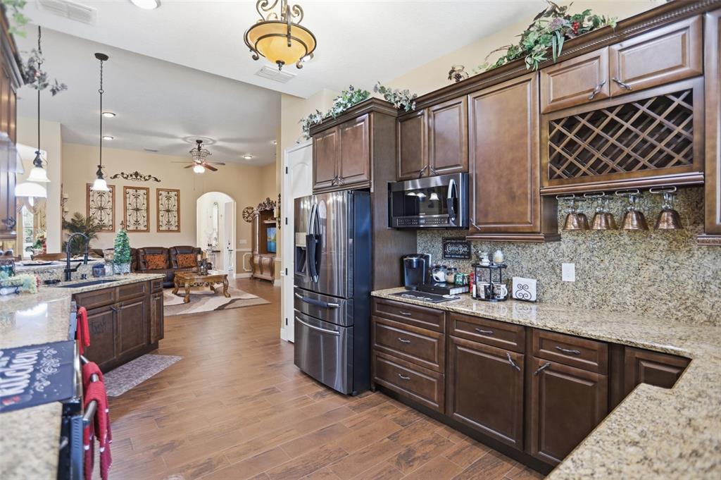13429 Montevista Road Clermont, FL 34711 - Photo 20 of 89 a kitchen with stainless steel appliances granite countertop a refrigerator a sink dishwasher a oven and a dining table with wooden floor