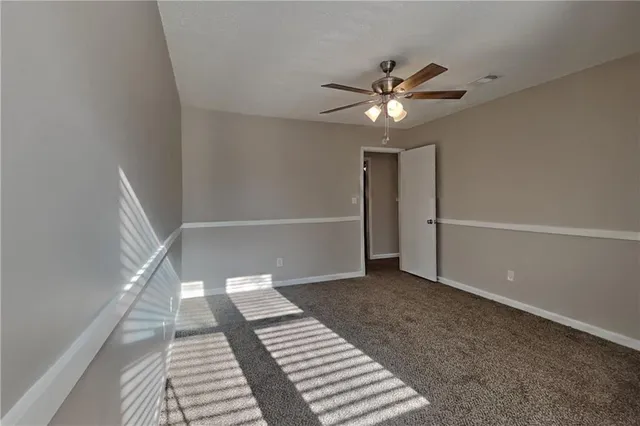 a view of an empty room with wooden floor and a ceiling fan