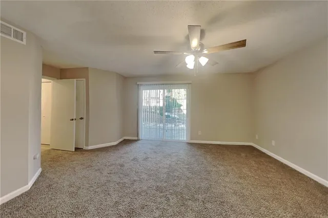 an empty room with chandelier fan and windows