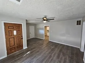 an empty room with wooden floor cabinet and windows