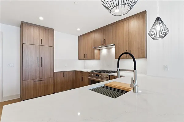 a large white kitchen with a large island oven a stove and white cabinets