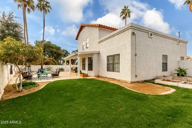 a view of a white house with a big yard and potted plants