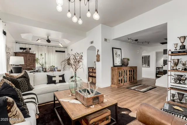 a living room with furniture kitchen view and a wooden floor