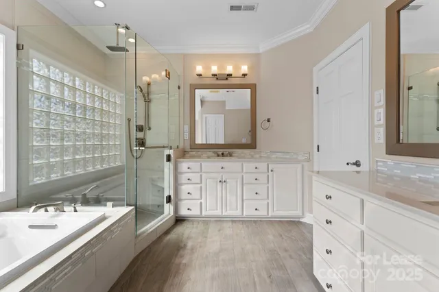 a bathroom with a granite countertop double vanity sink a mirror and a bathtub