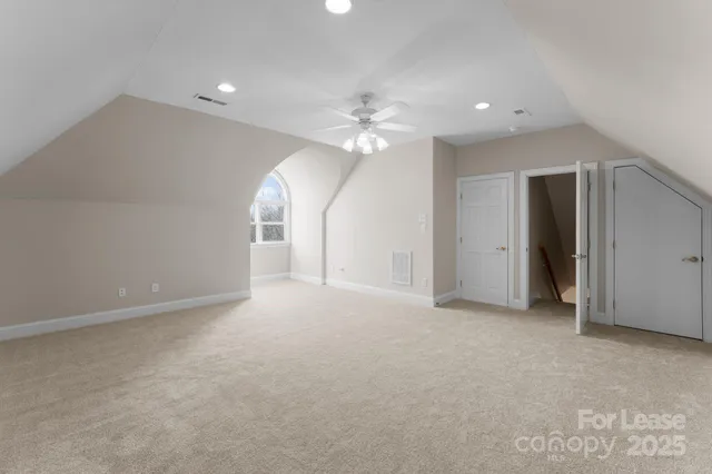 an empty room with chandelier fan and closet area
