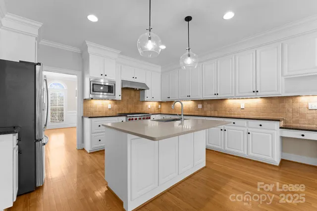 a kitchen with stainless steel appliances granite countertop a sink a stove a refrigerator and island with wooden floor