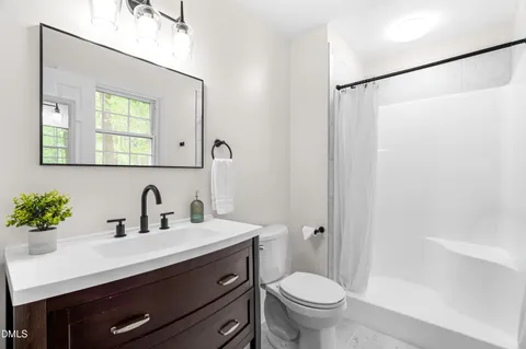 a bathroom with a sink a mirror a toilet and shower