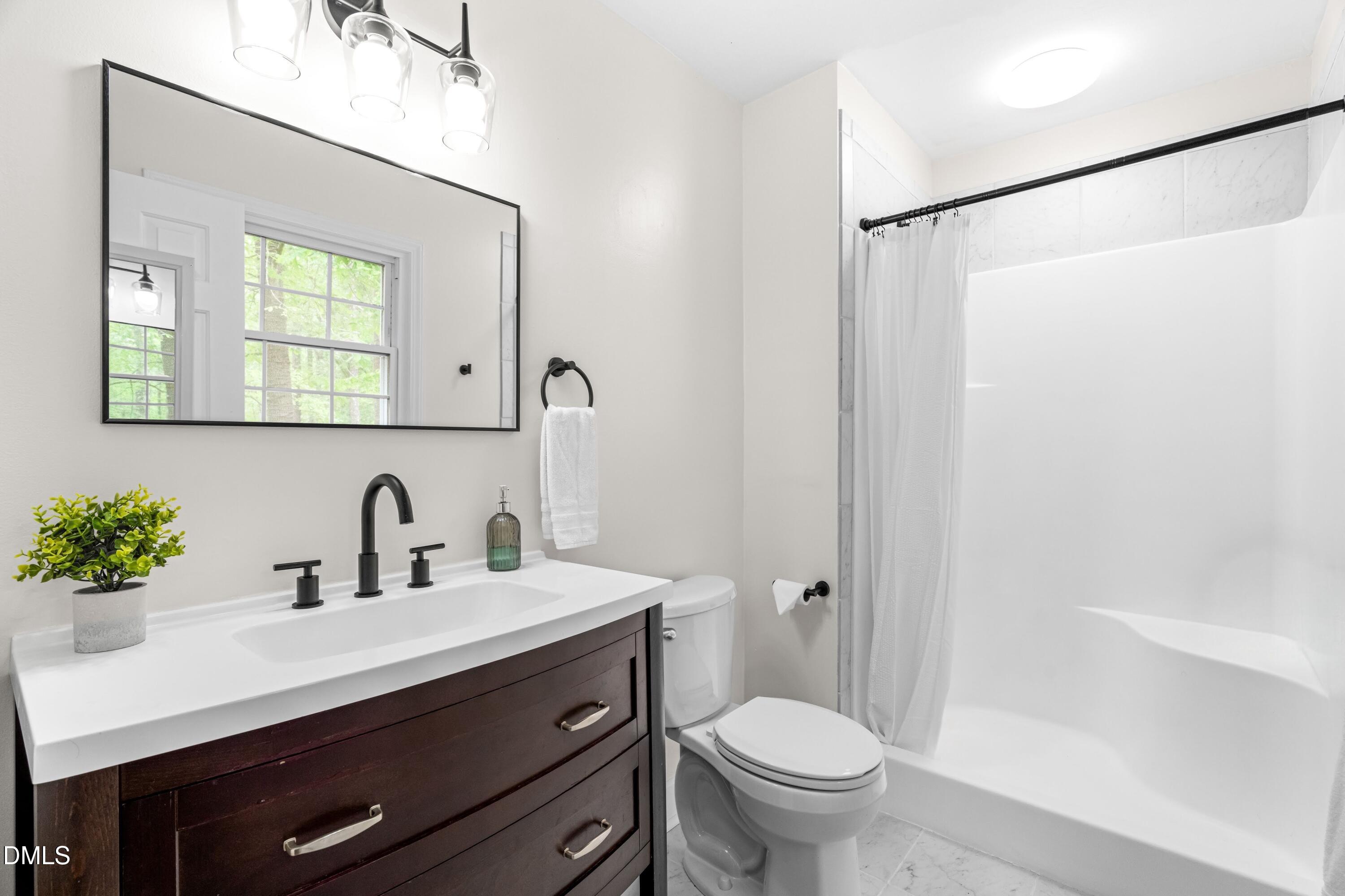 1109 Theresa Court Raleigh, NC 27615 - Photo 17 of 39 a bathroom with a sink a mirror a toilet and shower