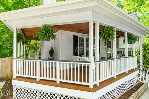 a white house that has a big yard with plants and trees
