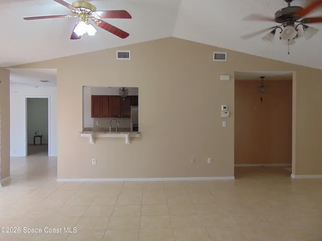 a view of an empty room with a chandelier fan