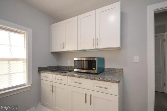 a kitchen with granite countertop white cabinets and a window