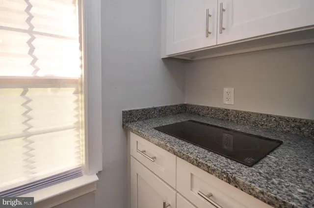 a kitchen with granite countertop white cabinets and a sink