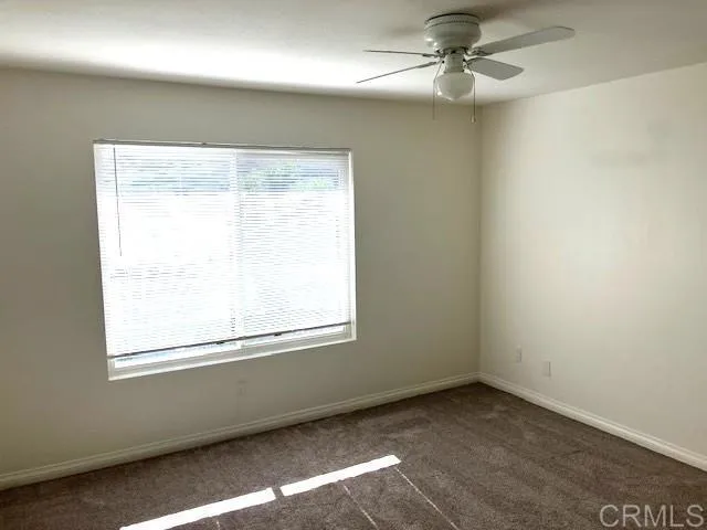 an empty room with a window and a fan