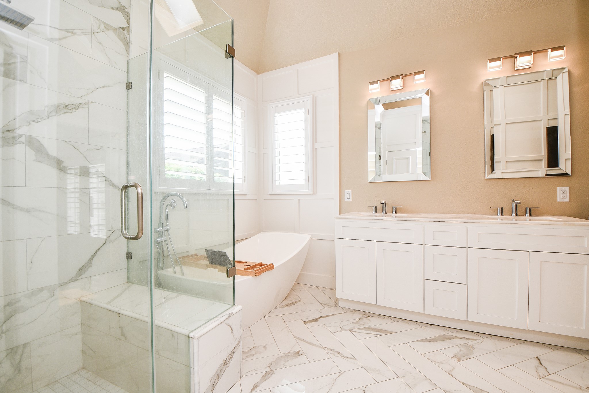 263 Wood Loop Street Houston, TX 77015 - Photo 32 of 45 This modern bathroom features a spacious glass-enclosed shower with marble tile, a freestanding bathtub by large windows, and a double vanity with elegant mirrors, offering a bright and luxurious feel.