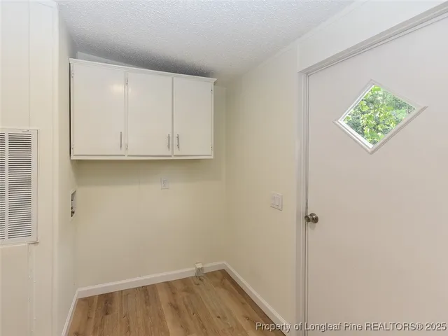 an empty room with wooden floor fireplace and windows